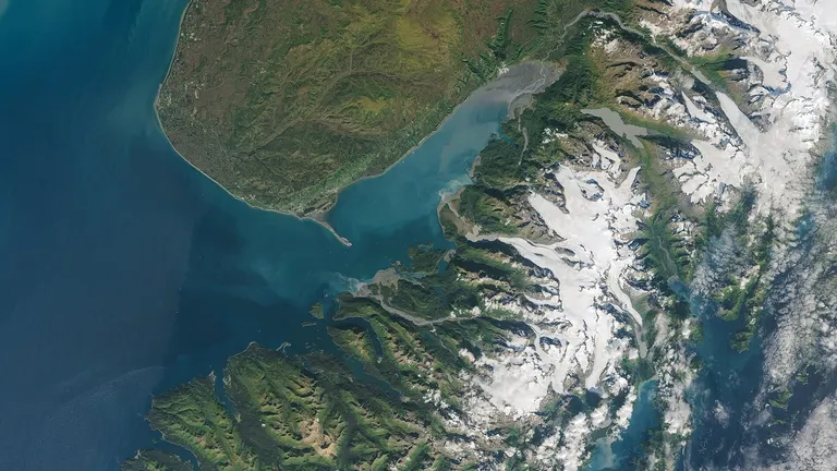 Satellite view of the Alaskan coast, glaciers and fjords running out to the deep blue of the shelf edge